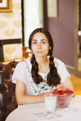 Healthy young woman is holding strawberries. Young woman is having healthy breakfast. Young woman eating strawberries