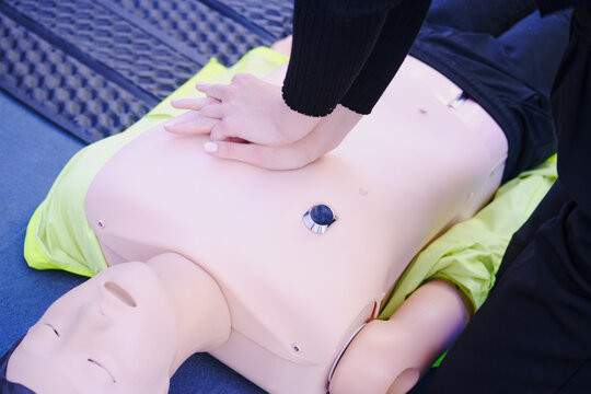 First aid training - CPR on a mannequin. Woman doing resuscitation to a training dummy in the emergency room