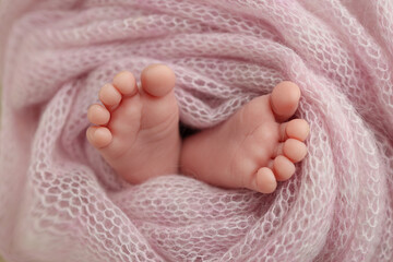 Close-up of tiny, cute, bare toes, heels and feet of a newborn girl, boy. Baby foot on pink soft...