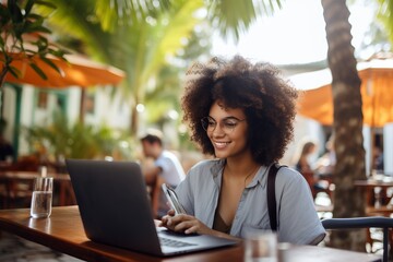 young afro woman working on her laptop in a terrace - obrazy, fototapety, plakaty