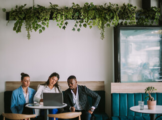 Beautiful business woman writing notes while her colleagues are looking at the notes while sitting at the cafe