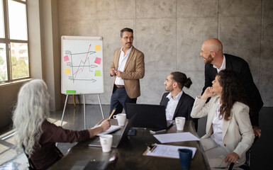 Businessman leading team through presentation at business meeting at workplace