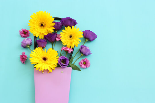 Top view image of pink, purple and yellow flowers composition over pastel blue background .Flat lay