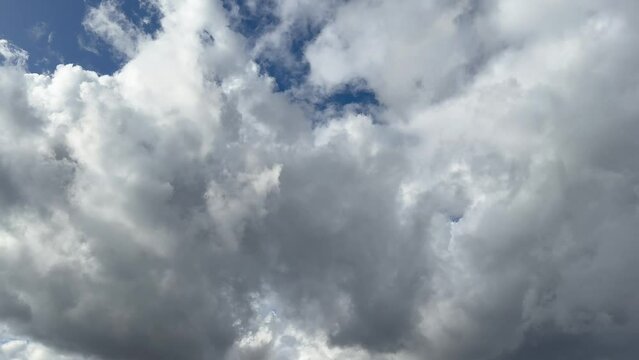 Cumulus white and gray clouds moving in blue sky approximating thunderstorm and rain. Cloud space background with dark, light and gray clouds. Change of weather in the autumn period. Nature, sky cloud