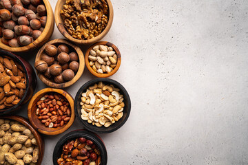 Assortment of nuts in bowls on white background top view with copy space. Healthy snack food.