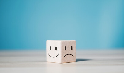 Mental health and emotional state concept, wooden block with smiley face and sad face icon.
