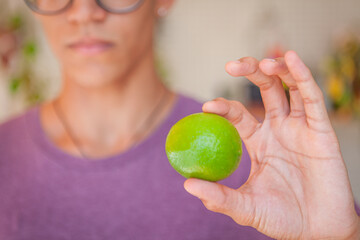 Close up of hands handling food. Hands of a young Brazilian man holding lemons with a blurred background and natural light.