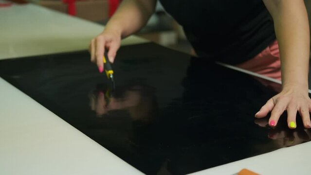 An employee of a print workshop tears off a vinyl film before gluing. Close up