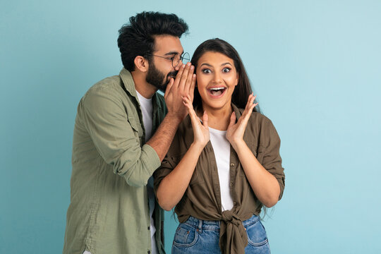 Middle eastern guy sharing secret with his excited pretty girlfriend