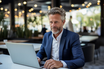 Mature business manager efficiently multitasks on laptop for various tasks 