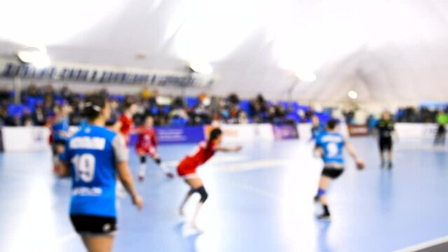 A women's sports team plays indoor handball. Blurry.