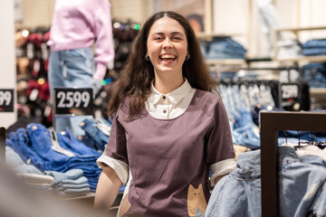 Portrait of happy Caucasian smiling woman posing in clothing store. Concept of sales and seasonal discounts