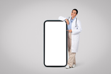 Latin woman doctor by huge cellphone with blank screen., mockup