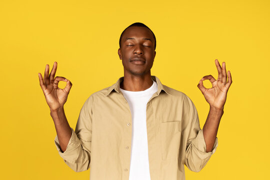 Calm millennial african american guy in casual with closed eyes, meditation, enjoy silence