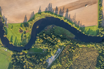 Beautiful aerial view of a snaking stream, snaky river, twisty river, forest and agriculture fields
