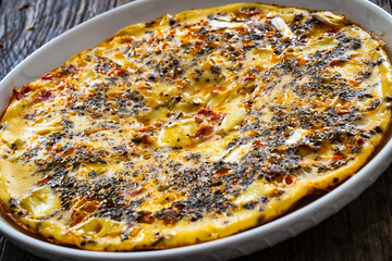 Omelette - scrambled eggs with camembert cheese and cured ham on wooden table
