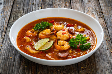 Louisiana soup gumbo with shrimp, chorizo and white rice on wooden table 