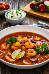 Louisiana soup gumbo with shrimp, chorizo and white rice on wooden table 