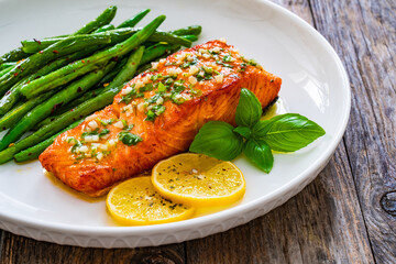 Seared salmon steak with green bean and lemons on wooden table
