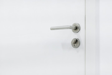 Metal door handle with lock on white wooden door. Close up of door handle on interio doors.