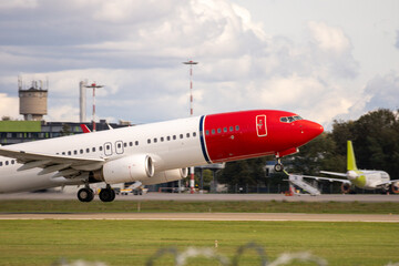 An aircraft with a red-colored bow takes off from the airfield runway