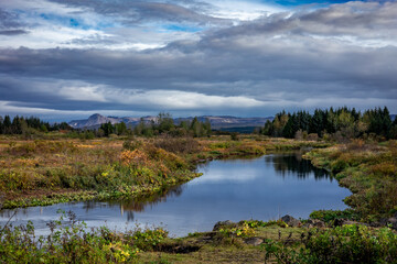 Autumnal landscape with Ellidaa river, forest and mountains in Reykjavik, Iceland. 