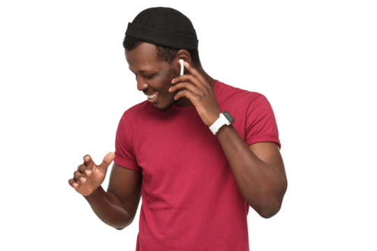 Young african american man dancing, enjoying music through wireless earphones