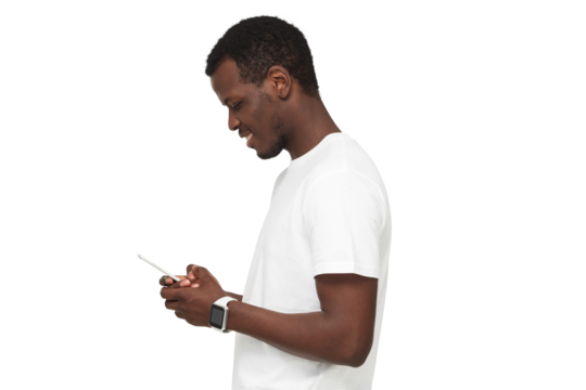 Side view of african american man standing, looking at screen of phone, surfing web and smiling while browsing content