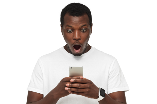 Close up portrait of handsome young african american man with mouth open, in blank white t shirt, holding smartphone, looking surprised and confused