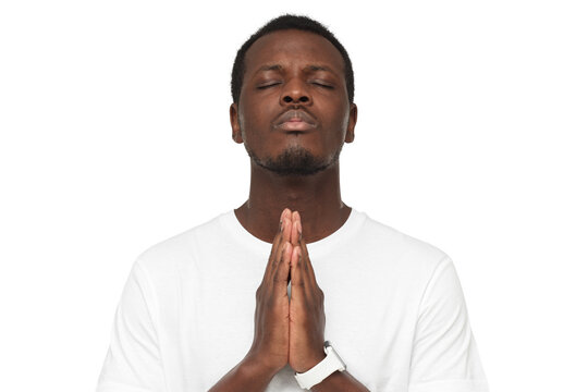 Close-up of young african man putting hands together, praying with closed eyes to find solution
