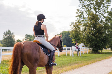 Girl in an equestrian outfit enjoying riding horseback along the trail, smiling and petting her...