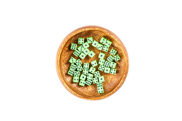 Handful of tiny green neon dice in a wooden cup isolated over white