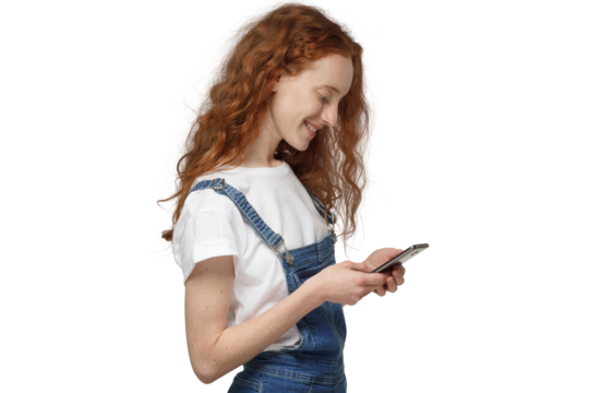 Side view of young redhead woman looking at phone while holding phone with both hands