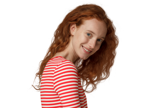 Young redhead woman turning shoulder to camera, smiling happily with her loose curly hair falling down