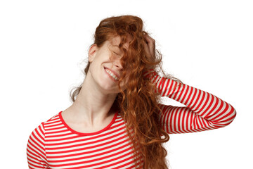 Close-up portrait of redhead teen girl pressing loose curly hair to her head creating messy hairstyle looking happy