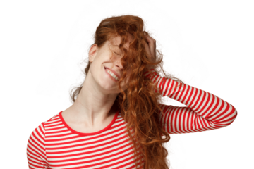 Close-up portrait of redhead teen girl pressing loose curly hair to her head creating messy hairstyle looking happy