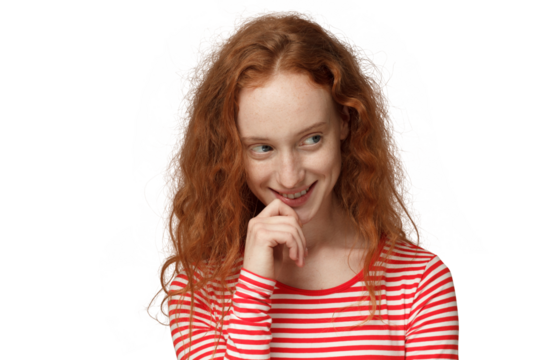Young beautiful woman with red loose curly hair touching lips with hand and looking away as if planning something interesting