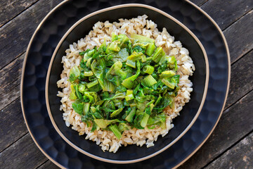 Brown rice topped with stir fry leaves of lettuce  and chicory.