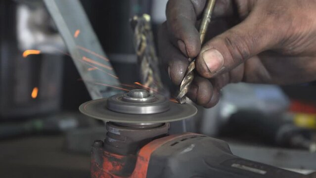 A master sharpens a drill using an emery disc. Sharpening a drill in a non-standard way using a metal-cutting tool