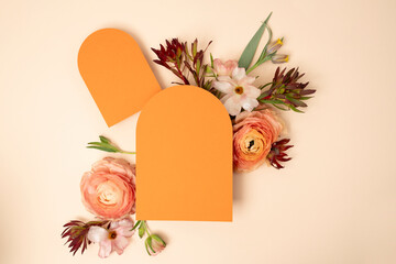 Wedding stationery flat lay with arched orange blank invitations and fresh ranunculus flowers