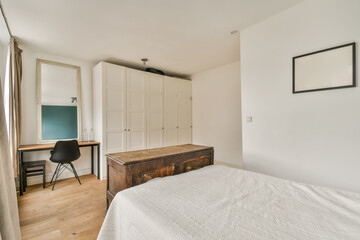 a bedroom with a bed, desk and mirror on the wall in front of the window looking out to the outside