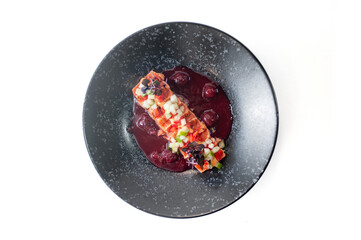 Salmon tataki in in cherry sauce on a black plate isolated