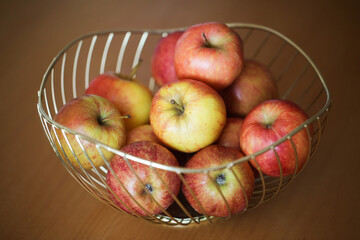 Apples in basket. Decorative metal bowl. Fruits on wooden table. Pile of apples.