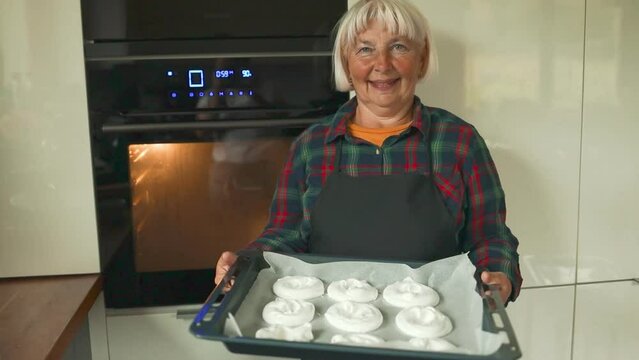 Woman baking white sweet meringues in the oven. White homemade bizet on the baking sheet. High quality FullHD footage