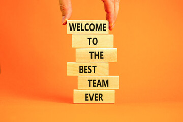 Welcome to best team symbol. Concept words Welcome to the best team ever on wooden block. Beautiful orange table background. Businessman hand. Business motivational and welcome to best team concept