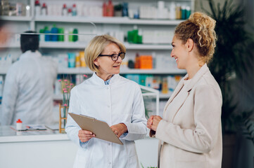 Portrait of a senior woman pharmacist and a female customer in a pharmacy