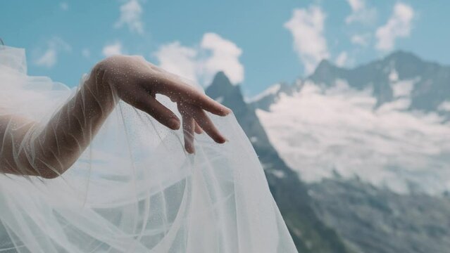 A woman's hand against a background of mountains reaches out to a man's hand