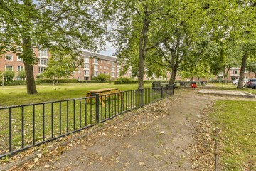 an empty park with trees and benches in the fore - image taken from google street view, looking south west