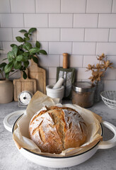 Cooking bread at home concept. The sourdough bread or artisan bread on the kitchen countertop with equipment. Vertical photo