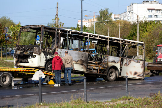 A completely burnt passenger bus is being loaded onto a tow truck.